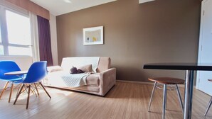 A modern living room with a beige sofa, blue chairs, a small table, and a framed picture on the wall. - Locking s Barro Preto 7 (Belo Horizonte)