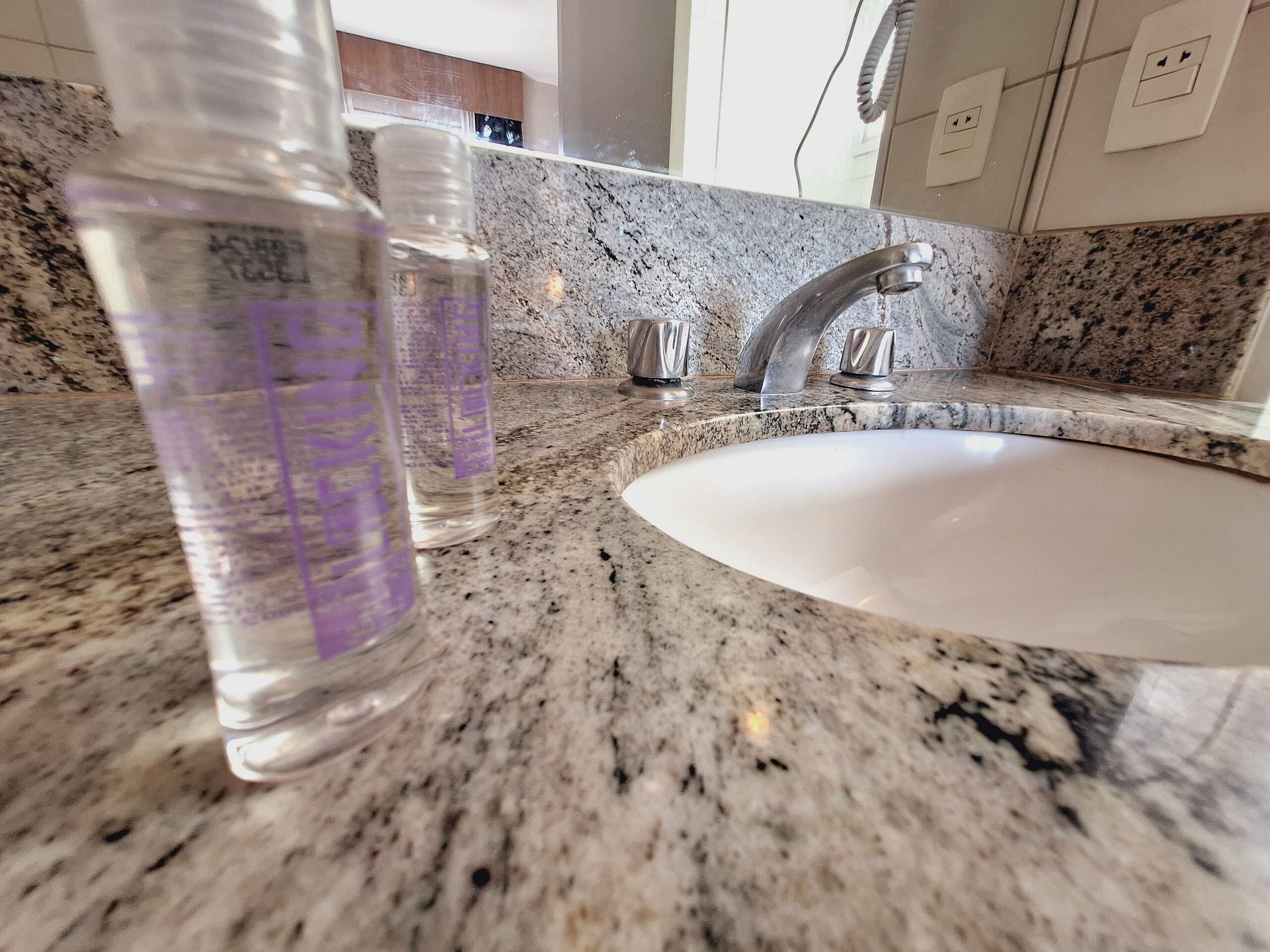 A bathroom with a granite countertop, a white sink, and a silver faucet.