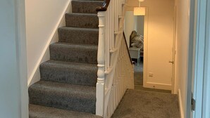 Una escalera empapelada con barandillas blancas y una barandilla de madera.