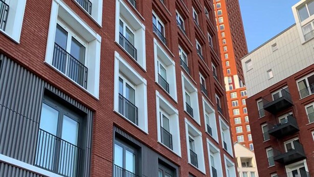 Un edificio de varios pisos con fachada de ladrillo rojo, ventanas grandes y balcones.