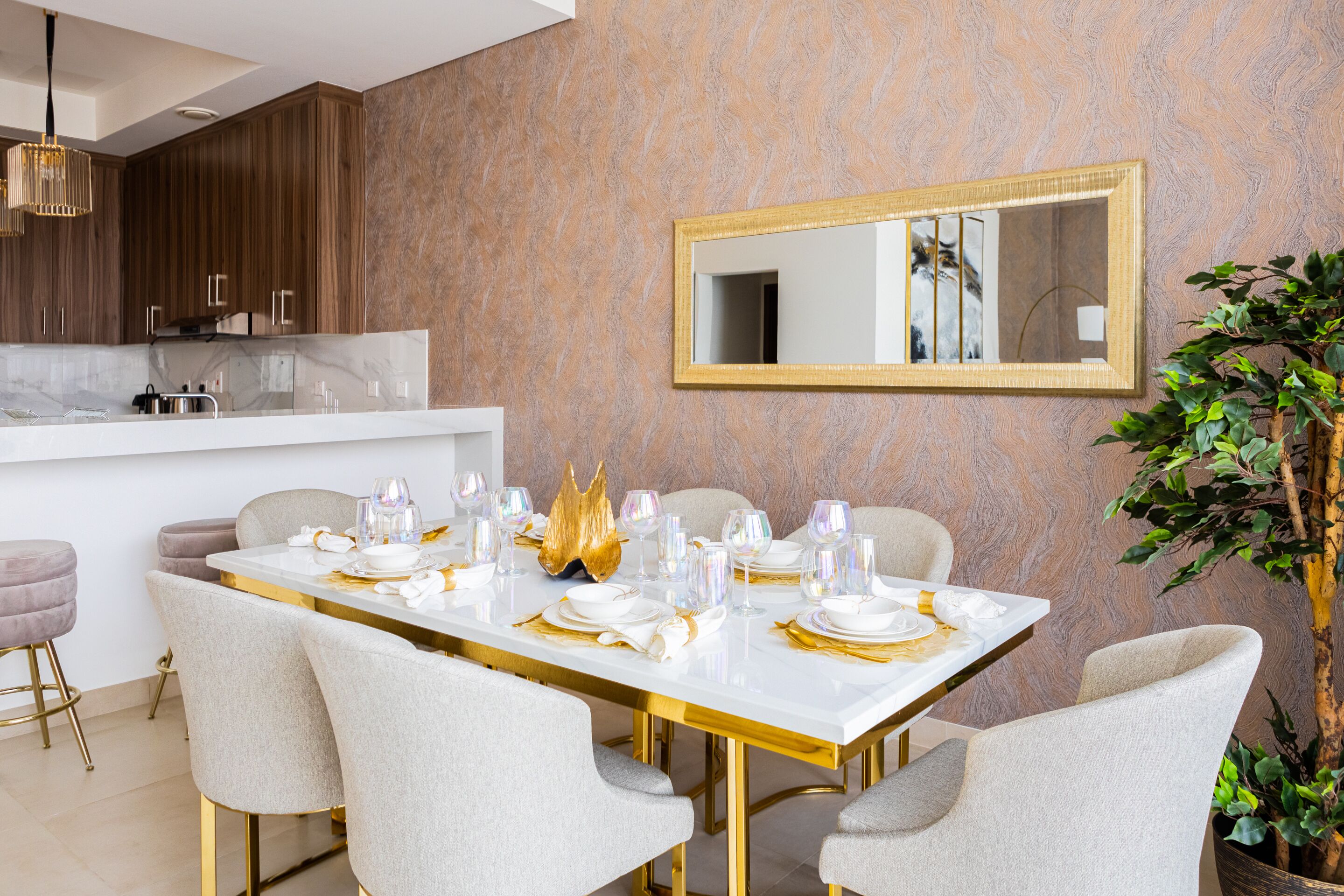 A modern dining area with a marble countertop, gold accents, and a large mirror on the wall.