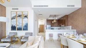 A modern living room with a sofa, armchairs, and a dining area with a table set for a meal. - Nasma Luxury Stays- Ras Al Khaimah (Ras Al Khaimah)