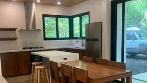 Une cuisine moderne avec un îlot central, des chaises en bois et une grande fenêtre.