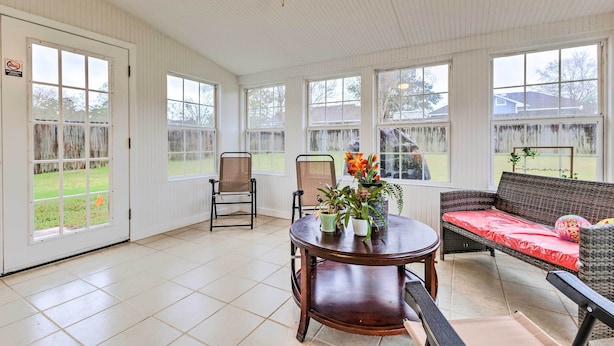 A covered patio area with a round wooden table, two chairs, a wicker sofa, and a potted plant. - Ocean Springs Home w/ Sunroom ~ 5 Mi to Beach (Ocean Springs)