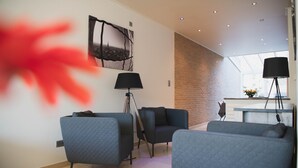 A modern living room with a large window, a black floor lamp, and a wall-mounted picture. - Spacious vacation home 5 min steps from city center. (Brugge)