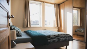 A bedroom with a bed, a nightstand, and a window with curtains. - Spacious vacation home 5 min steps from city center. (Brugge)