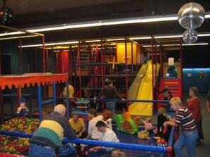Un área de juegos interior con diversas estructuras recreativas y una piscina de pelotas.