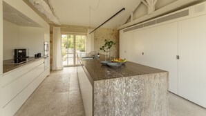 Una cocina moderna con una isla grande, armarios blancos y vistas al exterior.