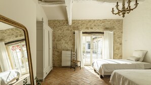 Un dormitorio con dos camas, un espejo grande, un radiador y vistas a través de una ventana con cortinas.