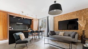 A modern living room with a sofa, chairs, a coffee table, and a kitchen area with a dining table. - Eiffel Tower - 4 bedrooms Air Conditioning (Paris)