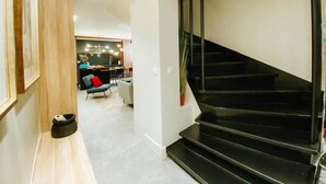 A modern interior with a staircase, a dining area, and a kitchen in the background. - Eiffel Tower - 4 bedrooms Air Conditioning (Paris)