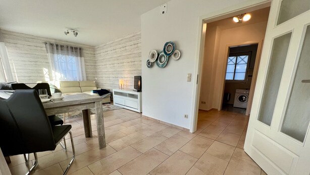 A modern living room with a dining area, a kitchen, and a laundry room.