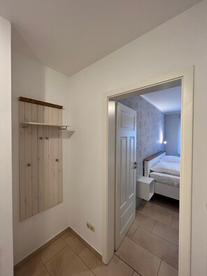A bedroom with a bed, a nightstand, and a wooden wardrobe.