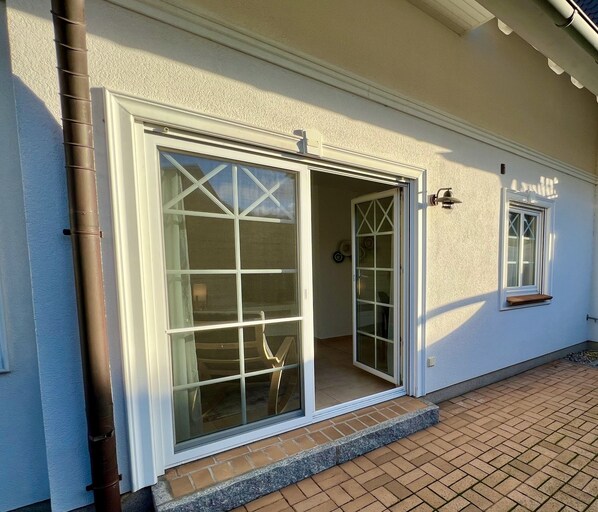 A building with a large sliding glass door and a smaller window, both with white frames.