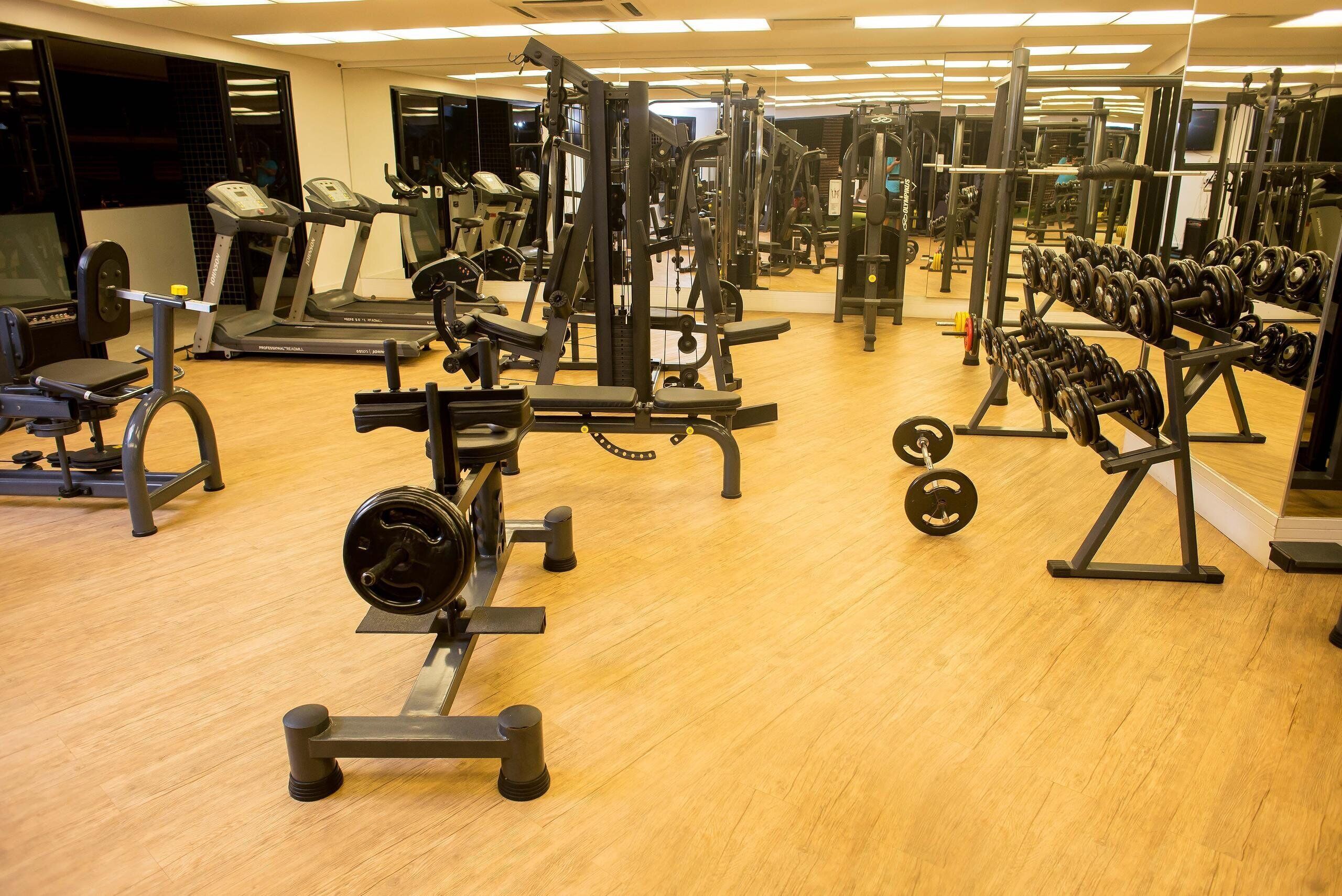 A gym with various exercise equipment, including treadmills, weight machines, and free weights.