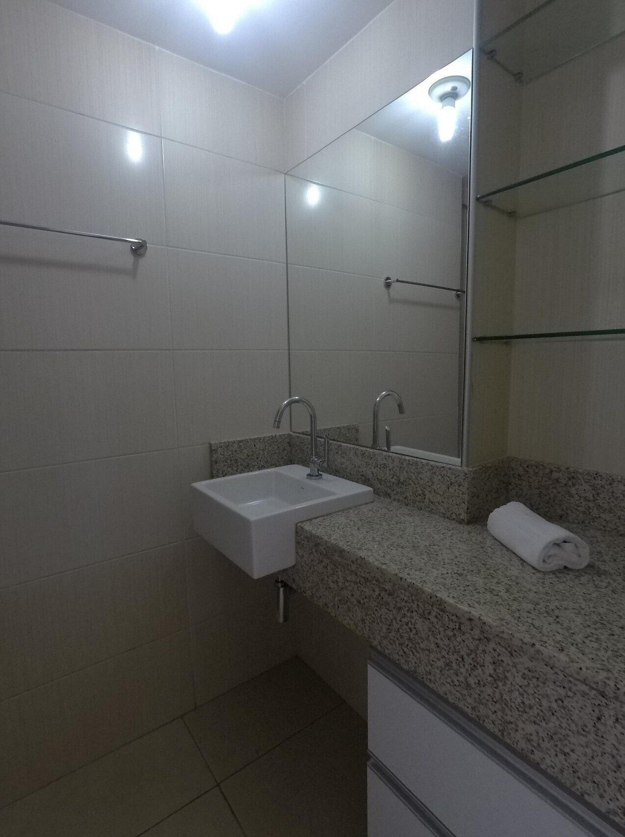 A bathroom with a white sink, granite countertop, and a mirror.