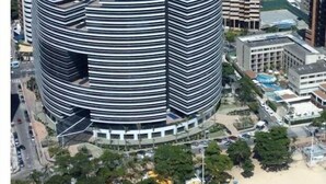 Un hotel moderno dal design circolare, immerso in un'area spiaggia con ombrelloni.