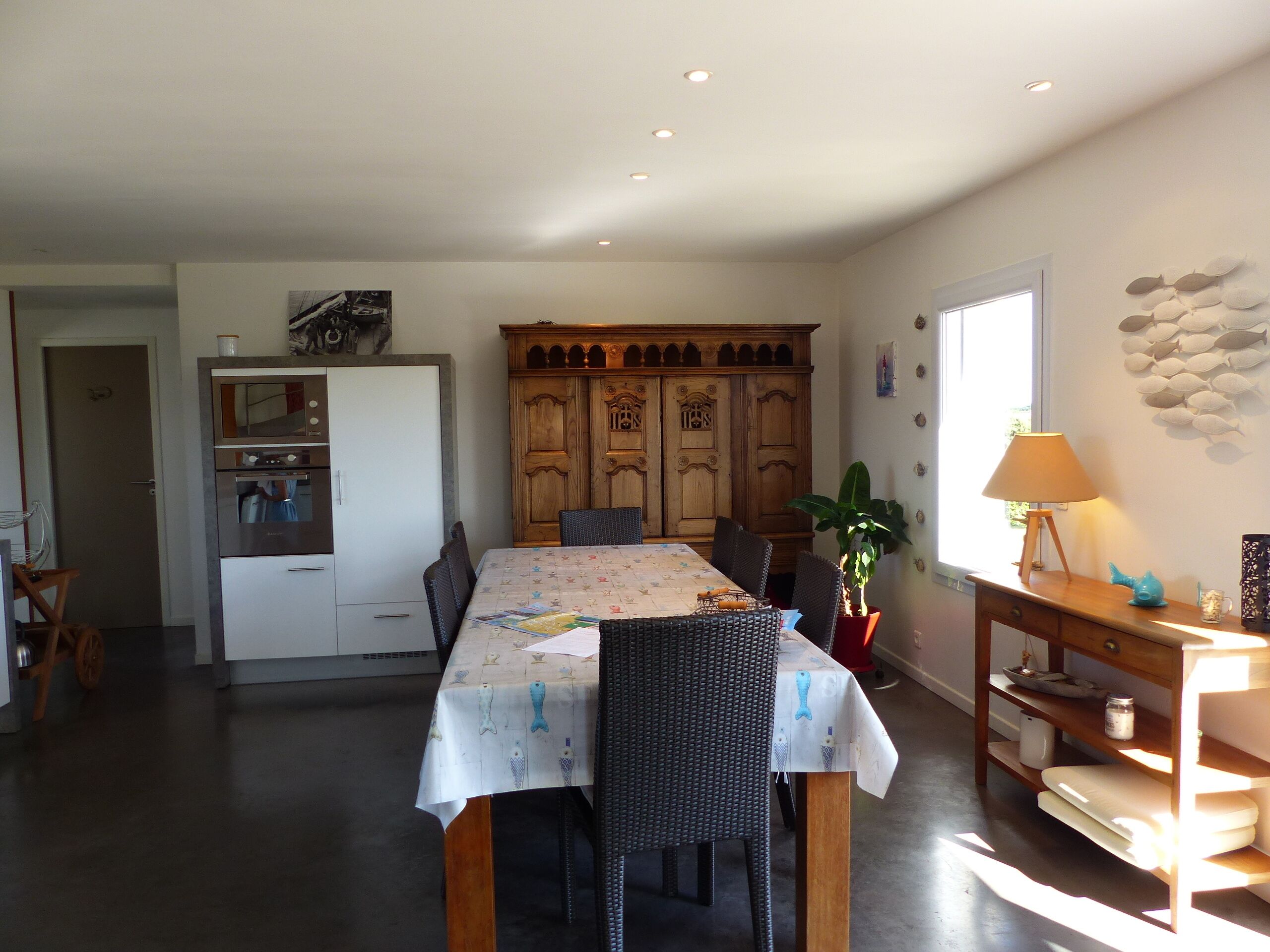 Een eethoek met een tafel voor vier personen, een houten kast en een koelkast.