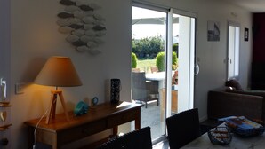 Een woonkamer met een tafel, stoelen, een lamp en een kunstwerk aan de muur.
