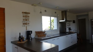 Een moderne keuken met een centraal eiland, een koffiezetapparaat en een bord met routeaanduidingen.