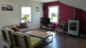 Een woonkamer met een bank, een televisie, een bijzettafeltje en een open haard.