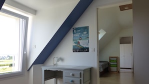 Een kamer met een bureau, een poster aan de muur en een raam.