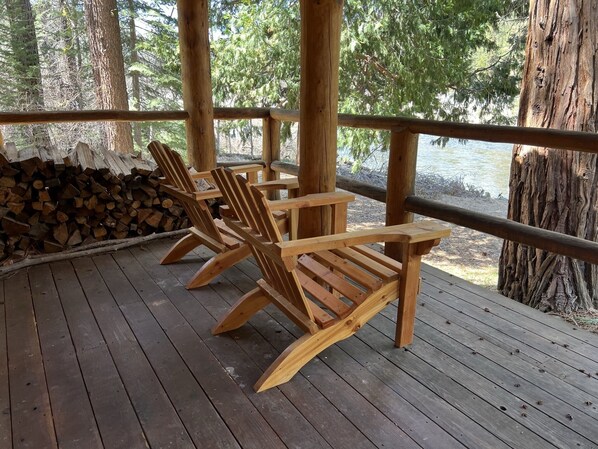 Relax on the deck with Adirondack chairs, surrounded by lush greenery and a serene water view.