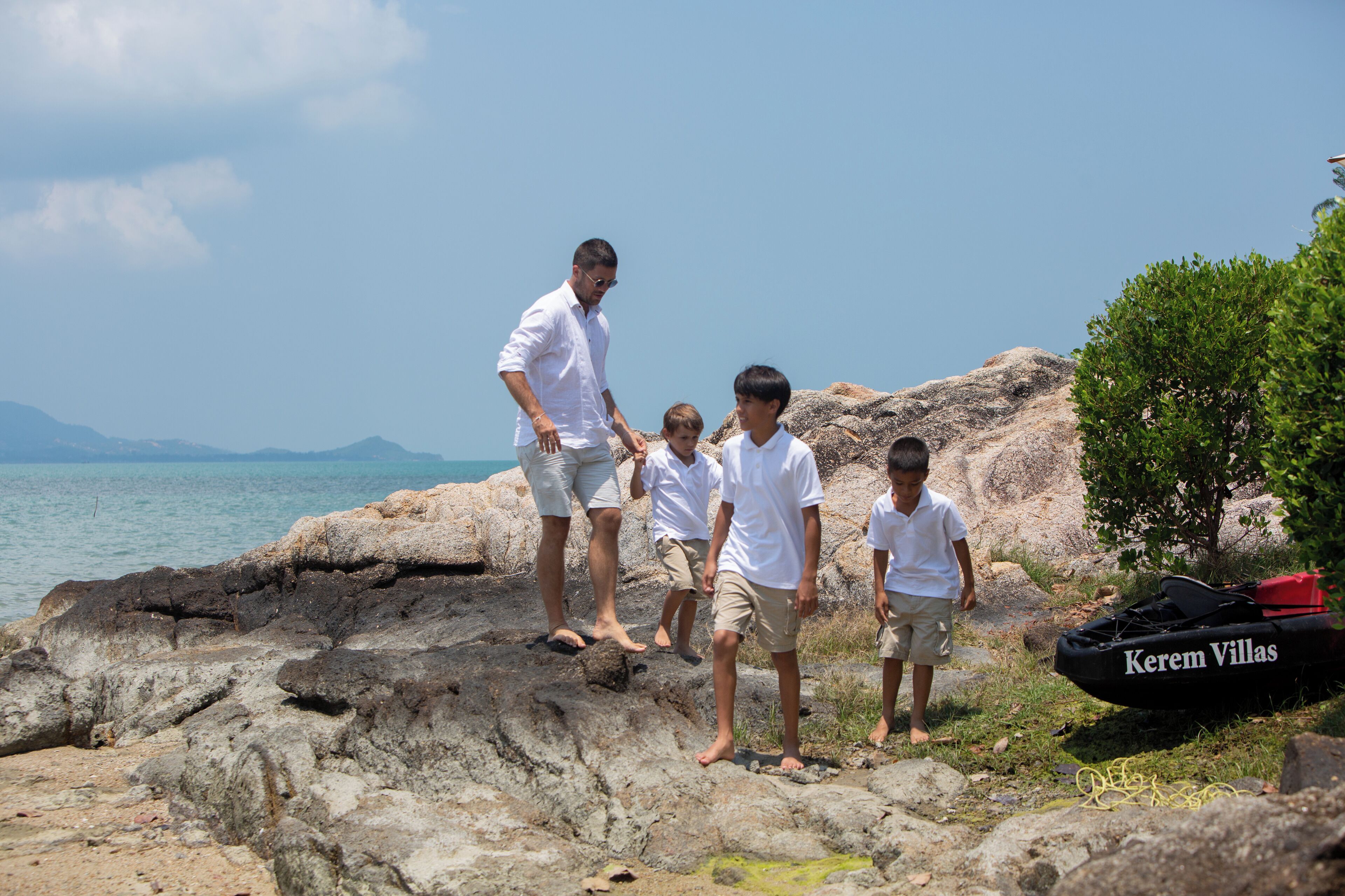 A rocky shoreline with a clear view of the sea and distant mountains.