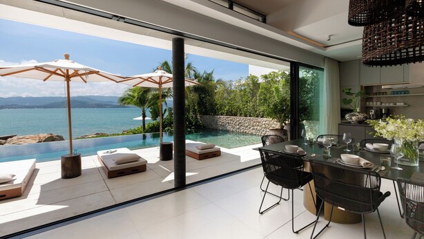 A modern outdoor dining area with a view of a pool and ocean. - Kerem Luxury Beachfront Villas (Koh Samui)