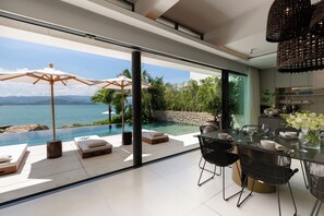 A modern outdoor dining area with a view of a pool and ocean. - Kerem Luxury Beachfront Villas (Koh Samui)