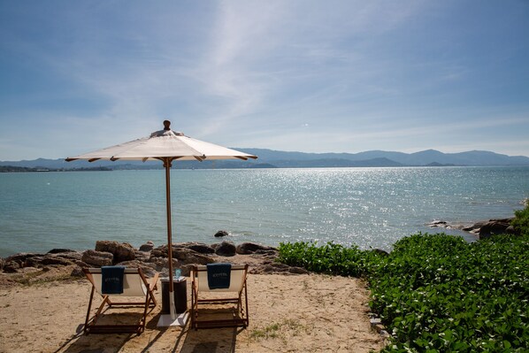 Playa privada, arena blanca, sillas reclinables de playa, sombrillas