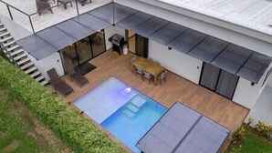 Une maison moderne dotée d’une piscine, d’un espace salon extérieur et d’un patio couvert.