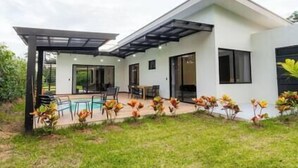 Une maison moderne à deux étages, dotée d’un patio couvert, d’une piscine et d’une pelouse bien entretenue.