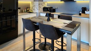 Una cocina moderna con una isla central, iluminación colgante y electrodomésticos integrados.
