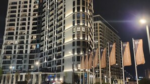 Un hotel de varios pisos con fachada curva, múltiples balcones y una entrada bien iluminada.
