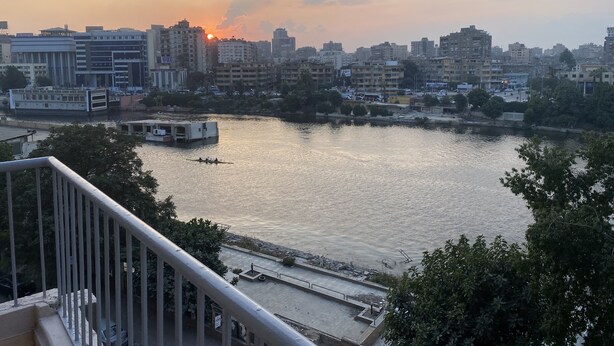 A river with boats, a city skyline, and a sunset. - Nile View Apartment - Sleeps 4 & Balcony (Cairo)