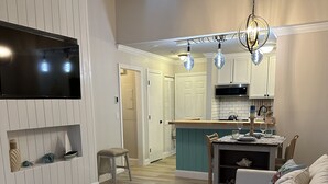 A modern living room with a sofa, coffee table, and a TV mounted on the wall. - Stylish 2nd floor Ocean Edge condo (Brewster)