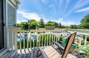 Enjoy a peaceful moment on this deck with a single chair, surrounded by lush potted plants and a view of the residential street.