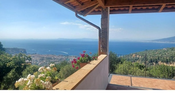 Un balcon avec vue sur la mer et un paysage montagneux.