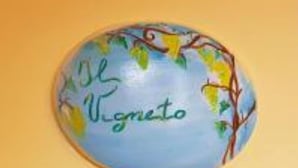 Un objet rond sur fond bleu, orné de motifs de feuilles vertes et jaunes, avec le mot « Vigneto » inscrit dessus.