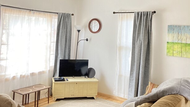 Ett vardagsrum med en soffa, en tv på ett tv-bord, ett litet bord och en tavla på väggen.