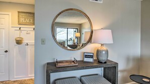 A reception area with a wooden console table, two cushioned seating, a mirror, a lamp, and a sign reading "Orthoslopes." - Wintergreen Resort Condo: Walk to Ski Lift! (Wintergreen Resort)