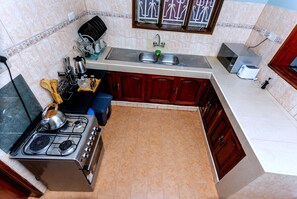 Une cuisine de taille réduite, équipée d’une cuisinière, d’un évier et d’un four à micro-ondes.