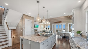 A spacious kitchen with a large island, wooden flooring, and pendant lighting. - 5BR Designer Home with Gulf Views, Elevator + Beach Access | Pelican Pointe (Destin)