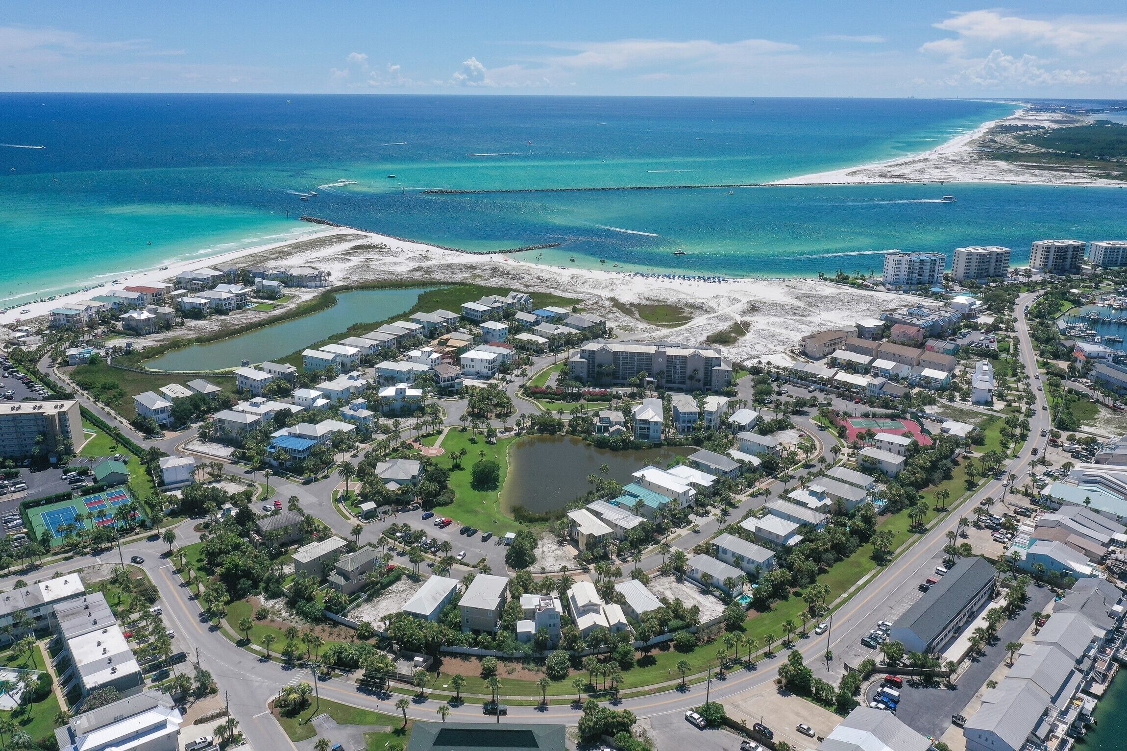Luftaufnahme einer Küstenwohngegend mit mehreren Gebäuden, Straßen und einem Strand.