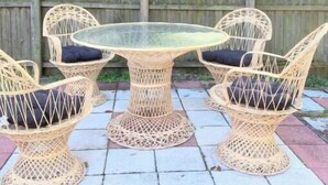 A wicker outdoor table and chairs set on a tiled patio with a wooden fence in the background. - Sunshine Escape Guesthouse ☀ (Orlando)