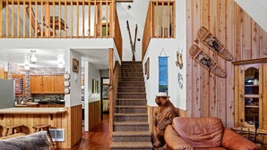 Amplia sala de estar con una escalera de madera, un sofá de cuero y una estatua de un oso.
