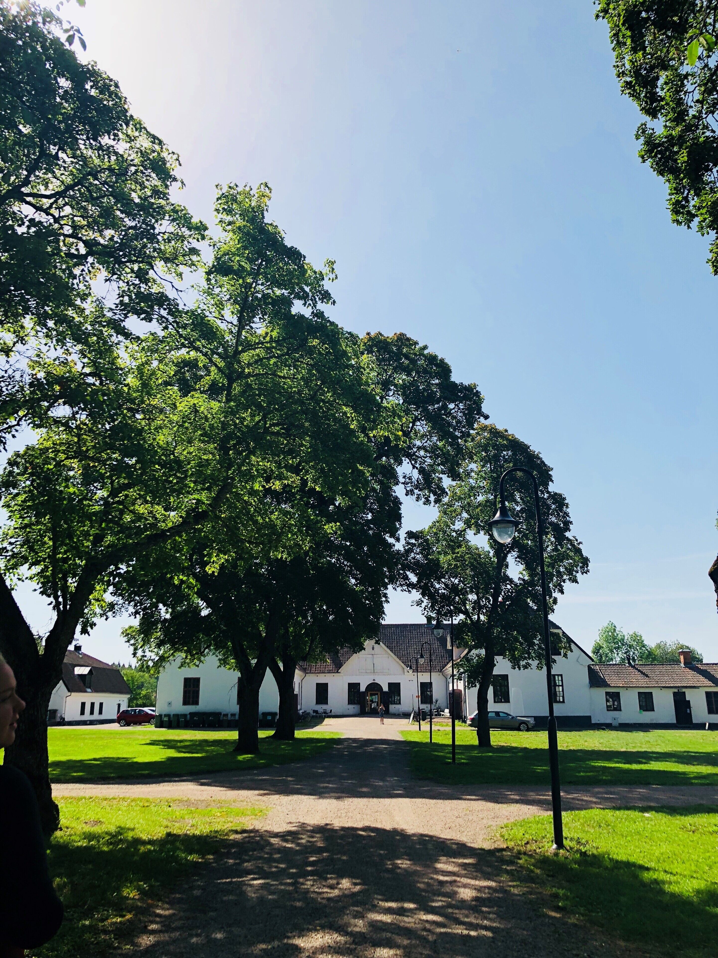 A courtyard with a building, trees, and a clear sky.