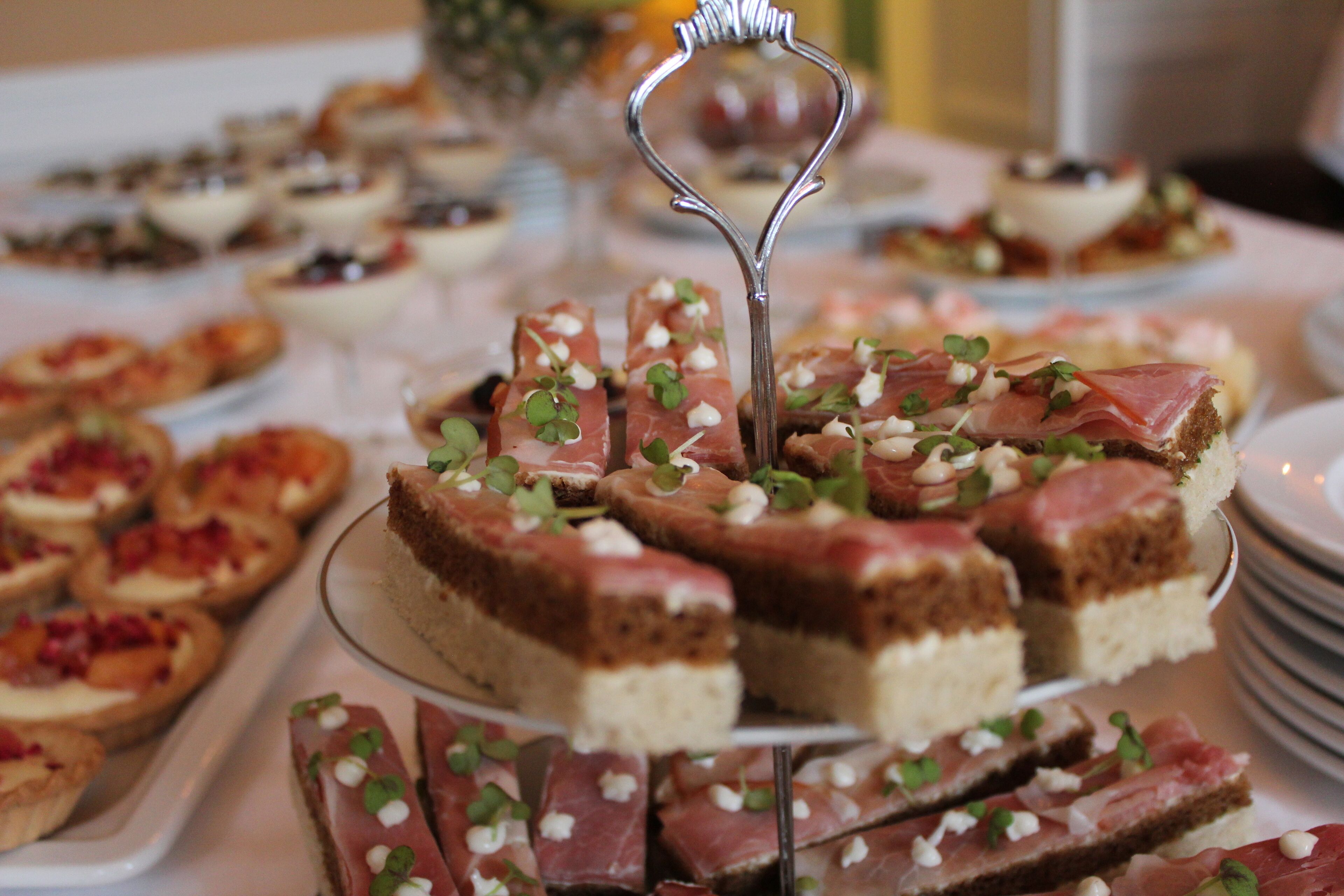 Diversas sobremesas em uma mesa de buffet, incluindo fatias de bolo com guarnição verde e um garfo decorativo.