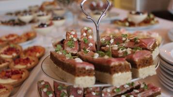 Diversas sobremesas em uma mesa de buffet, incluindo fatias de bolo com guarnição verde e um garfo decorativo.